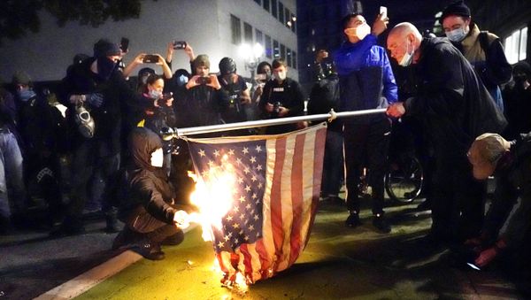 A protester lights an American flag on fire during a demonstration on 4 November 2020 in Portland, Oregon. - Sputnik International