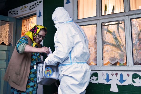 A member of a local electoral commission wearing personal protective equipment (PPE) holds a mobile ballot box as a woman casts her vote in Moldova's presidential election in the village of Stetcani, some 40 km north of Chisinau, on 1 November 2020, amid the ongoing coronavirus disease pandemic.  - Sputnik International