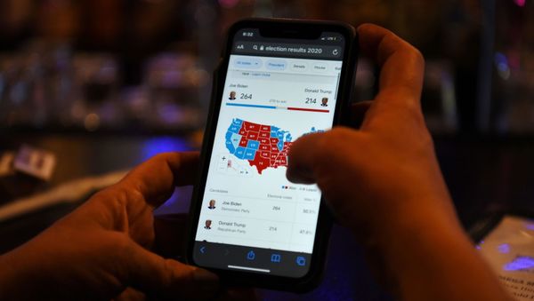 A woman uses her mobile phone to check the election results as Joe Biden’s lead increases, in Houston, Texas, U.S., November 6, 2020.  - Sputnik International