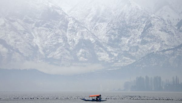 A Kashmiri boatman paddles a shikara boat during rainfall on Dal Lake in Srinagar on January 21, 2019. - Sputnik International