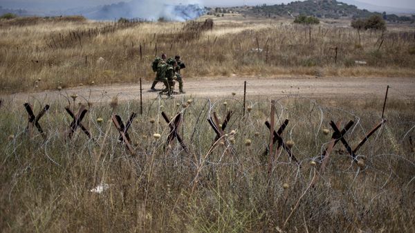 Israeli soldiers walk back from a position on the border with Syria on the Israeli controlled Golan Heights as smoke rises following explosions, Tuesday, July 16, 2013. - Sputnik International