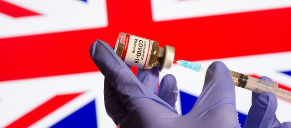 A woman holds a small bottle labeled with a Coronavirus COVID-19 Vaccine sticker and a medical syringe in front of displayed UK flag in this illustration taken, October 30, 2020 - Sputnik International