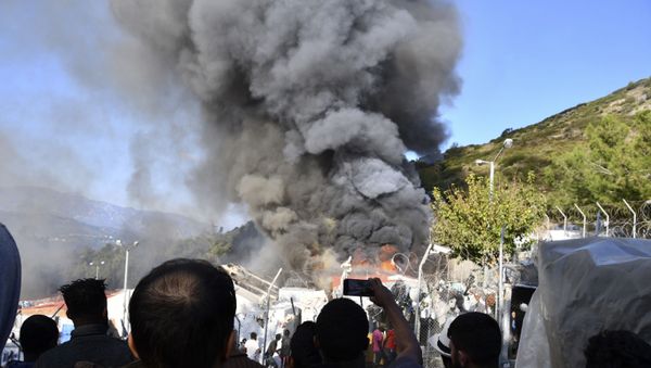 Migrants watch smoke rising from a fire inside a refugee camp on the eastern Aegean island of Samos, Greece, Wednesday, Nov. 11, 2020. Dozens of accommodations were destroyed by the fire that broke out on Wednesday morning, two weeks after an earthquake hit the island.  - Sputnik International