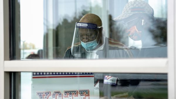 Poll worker Van Paterson assists an early voter with a voting machine inside the Milwaukee Public Library’s Good Hope branch, on the first day of in-person voting in Wisconsin, U.S., October 20, 2020. - Sputnik International