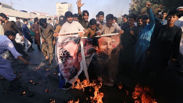 People chant slogans as they set fire to a banner with an image of French President Emmanuel Macron during a protest against cartoon publications of Prophet Mohammad in France and French President Emmanuel Macron's comments, in Peshawar, Pakistan 27 October 2020. - Sputnik International