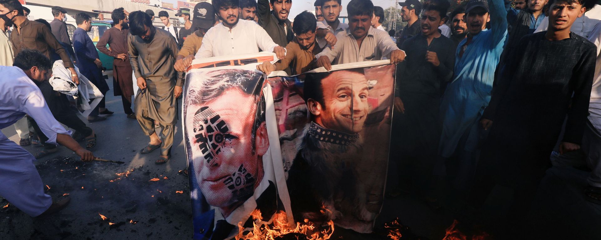 People chant slogans as they set fire to a banner with an image of French President Emmanuel Macron during a protest against cartoon publications of Prophet Mohammad in France and French President Emmanuel Macron's comments, in Peshawar, Pakistan 27 October 2020. People chant slogans as they set fire to a banner with an image of French President Emmanuel Macron during a protest against cartoon publications of Prophet Mohammad in France and French President Emmanuel Macron's comments, in Peshawar, Pakistan 27 October 2020. - Sputnik International, 1920, 22.11.2020