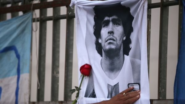 A rose is placed next to a banner of Argentine soccer great Diego Maradona as fans gather to mourn his death, at the Obelisk of Buenos Aires, Argentina November 25, 2020 - Sputnik International