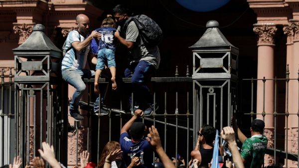 Men help a child to climb on the fence of the Casa Rosada presidential palace as people gather to mourn the death of soccer legend Diego Armando Maradona, in Buenos Aires, Argentina November 26, 2020. - Sputnik International