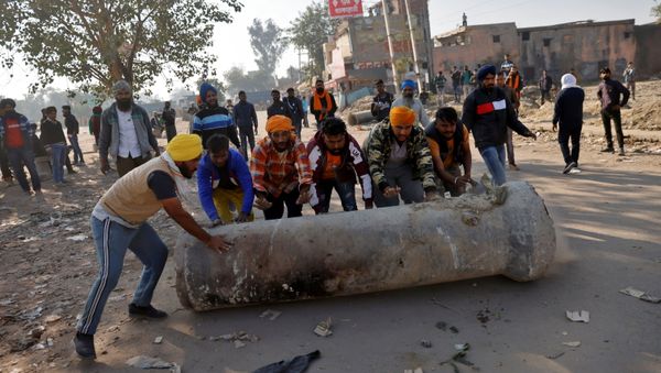 Farmers push a cement pipe to use it as a roadblock during a protest against the newly passed farm bills at Singhu border near Delhi Farmers push a cement pipe to use it as a roadblock during a protest against the newly passed farm bills at Singhu border near Delhi - Sputnik International