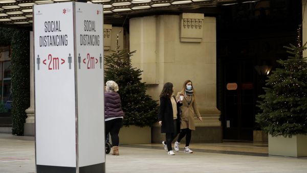 A woman wearing a face mask walks past Christmas trees and a social distancing sign outside the Selfridges department store on Oxford Street, which is temporarily closed for in-store browsing with online collection possible from a collection point, during England's second coronavirus lockdown, in London, Monday, Nov. 23, 2020 A woman wearing a face mask walks past Christmas trees and a social distancing sign outside the Selfridges department store on Oxford Street, which is temporarily closed for in-store browsing with online collection possible from a collection point, during England's second coronavirus lockdown, in London, Monday, Nov. 23, 2020 - Sputnik International