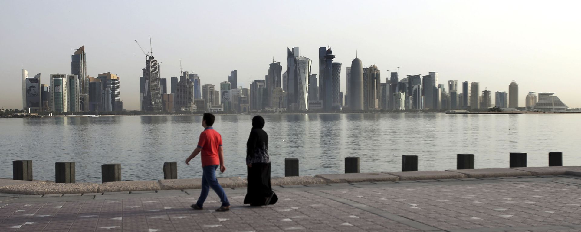 In this Friday, May 4, 2018, photo, a couple walk by the sea with the city skyline in the background, in Doha, Qatar In this Friday, May 4, 2018, photo, a couple walk by the sea with the city skyline in the background, in Doha, Qatar - Sputnik International, 1920, 02.02.2021