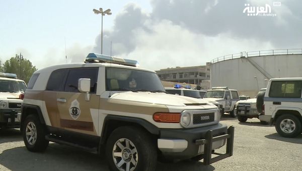 In this image made from a video broadcast on the Saudi-owned Al-Arabiya satellite news channel on Saturday, Sept. 14, 2019, a Saudi police cruiser sits in a parking lot as the smoke from a fire at the Abqaiq oil processing facility can be seen behind it in Buqyaq, Saudi Arabia - Sputnik International