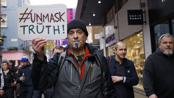 A protester holds up a placard as he takes part in an anti-lockdown riot against government restrictions designed to control the spread of coronavirus, including the wearing of masks and lockdowns, in London on 28 November 2020. - Sputnik International