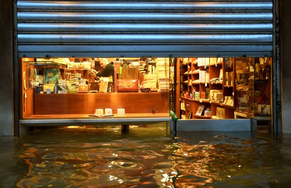 A shopkeeper tries to prevent water from getting into his shop, Venice A shopkeeper tries to prevent water from getting into his shop, Venice - Sputnik International