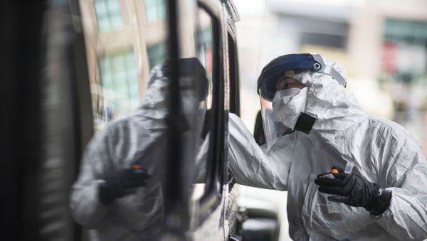 A passenger gets swabbed for COVID-19 at a testing site at the convention center in Providence, R.I, Tuesday, Dec. 1, 2020 - Sputnik International