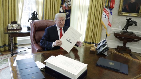 President Donald Trump displays the $1.5 trillion tax overhaul package he had just signed, Friday, Dec. 22, 2017, in the Oval Office of the White House in Washington. The bill provides generous tax cuts for corporations and the wealthiest Americans, plus smaller cuts for middle- and low-income families. President Donald Trump displays the $1.5 trillion tax overhaul package he had just signed, Friday, Dec. 22, 2017, in the Oval Office of the White House in Washington. The bill provides generous tax cuts for corporations and the wealthiest Americans, plus smaller cuts for middle- and low-income families. - Sputnik International