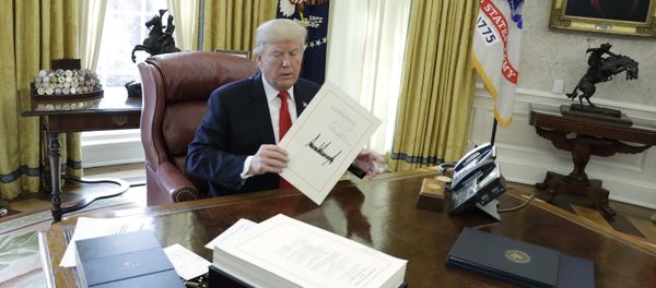 President Donald Trump displays the $1.5 trillion tax overhaul package he had just signed, Friday, Dec. 22, 2017, in the Oval Office of the White House in Washington. The bill provides generous tax cuts for corporations and the wealthiest Americans, plus smaller cuts for middle- and low-income families. - Sputnik International