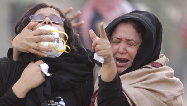 Anti-government protesters react to tear gas fired by riot police during clashes on Saturday, 17 December 2011 in Abu Saiba village west of the capital of Manama, Bahrain. It was the third straight day of clashes along the main highway where protesters were trying to stage sit-ins against the government. - Sputnik International