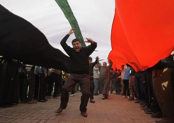 Protesters chant anti-Iraqi government slogans under a huge Iraqi flag during a protest in Tahrir Square in Baghdad, Iraq, Wednesday, 23 February 2011 Protesters chant anti-Iraqi government slogans under a huge Iraqi flag during a protest in Tahrir Square in Baghdad, Iraq, Wednesday, 23 February 2011 - Sputnik International