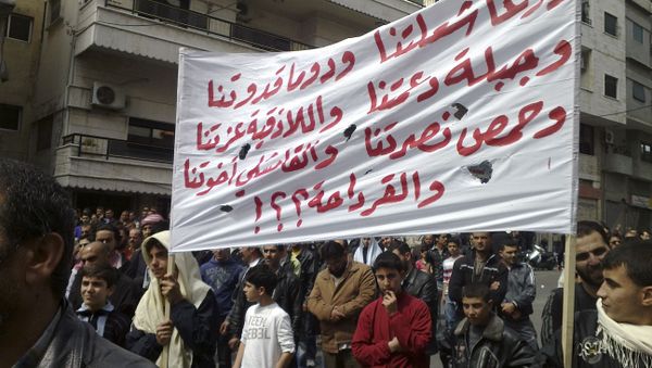 In this citizen journalism image made on a mobile phone and acquired by the AP, Syrian anti-government protesters carry a banner in Arabic that reads: Daraa is our torch, Douma is our model, Jabla is our support, Latakia is our pride, Homs is our victory, in Qamishli our brothers and what about Qardaha ??!, knowing that Qardaha is the home village of Syrian President Bashar Assad, as they gather in the coastal city of Banias, Syria, Friday, April 22, 2011 - Sputnik International