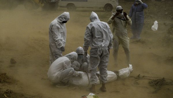 Relatives wearing protective gear tie up the dead body  before the burial at a graveyard in New Delhi (File) - Sputnik International