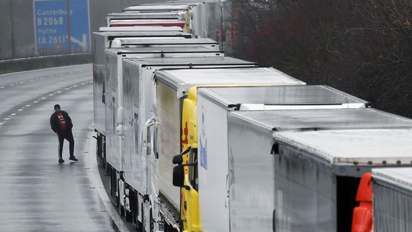 A driver walks next to lorries parked on the M20 motorway towards Eurotunnel and the Port of Dover, as EU countries impose a travel ban from the UK following the coronavirus disease (COVID-19) outbreak, in Folkestone, Britain, December 21, 2020. REUTERS/Toby Melville - Sputnik International