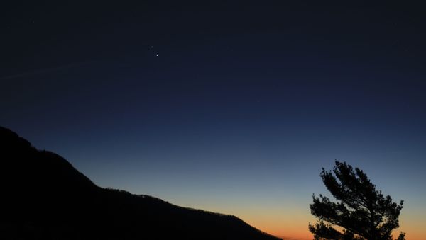 Saturn, top, and Jupiter, below, are seen after sunset from Shenandoah National Park, Sunday, Dec. 13, 2020, in Luray, Virginia. The two planets are drawing closer to each other in the sky as they head towards a “great conjunction” on December 21, where the two giant planets will appear a tenth of a degree apart. - Sputnik International