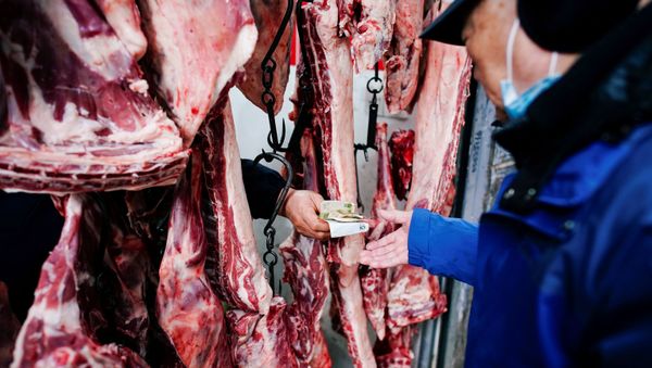 A vendor holds Chinese yuan notes as a customer pays for lamb at a wet market almost a year after the global outbreak of the coronavirus disease (COVID-19) in Wuhan, Hubei province, China December 7, 2020 - Sputnik International