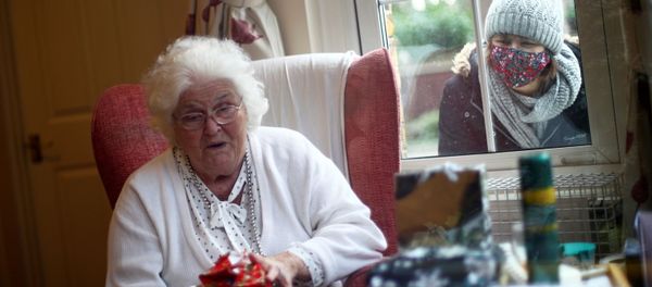 Nicky Clough looks through the window at her mother Pam Harrison opening a present on Christmas Day at Alexander House Care Home, as the spread of the coronavirus disease (COVID-19) continues, in Wimbledon, London, Britain, December 25, 2020 Nicky Clough looks through the window at her mother Pam Harrison opening a present on Christmas Day at Alexander House Care Home, as the spread of the coronavirus disease (COVID-19) continues, in Wimbledon, London, Britain, December 25, 2020 - Sputnik International