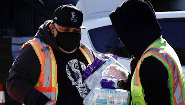 Volunteer Ismael Izzy Barrera, 45, helps load a Los Angeles Regional Food Bank patron's vehicle with food and diapers at a drive-thru food distribution, as the U.S. Senate grapples with whether to increase payments to Americans reeling from the coronavirus disease (COVID-19) pandemic, in West Covina, California, U.S. December 29, 2020.   - Sputnik International