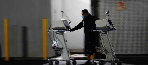 A hospital worker pushes two Computer on Wheels (COW) workstations outside the emergency room at the Community Hospital of Huntington Park during a surge in positive coronavirus cases in Huntington Park, California, U.S. December 29, 2020 - Sputnik International