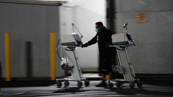 A hospital worker pushes two Computer on Wheels (COW) workstations outside the emergency room at the Community Hospital of Huntington Park during a surge in positive coronavirus cases in Huntington Park, California, U.S. December 29, 2020 - Sputnik International