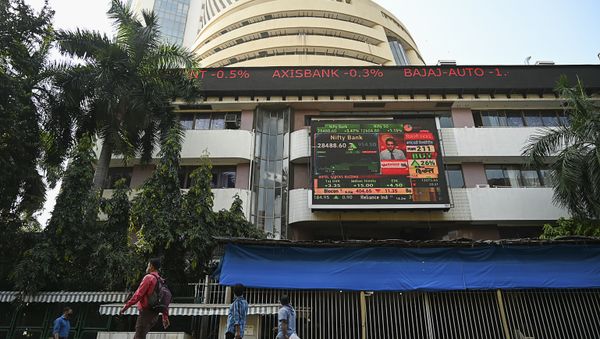 Pedestrians walk past share prices on a digital broadcast outside the Bombay Stock Exchange (BSE) in Mumbai on November 10, 2020.  - Sputnik International