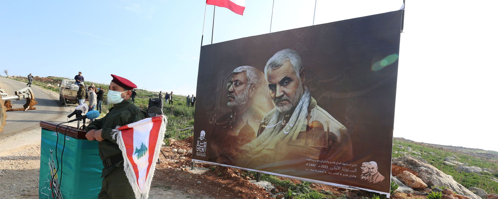 A member of Lebanon's Hezbollah holds a Lebanese flag as he stands in front of a picture depicting senior Iranian military commander General Qassem Soleimani and Iraqi militia commander Abu Mahdi al-Muhandis who were killed in a U.S. attack, during a ceremony marking the first anniversary of their killing, in the southern village of Khiam, Lebanon January 3, 2021. REUTERS/Aziz Taher - Sputnik International, 1920, 07.01.2022