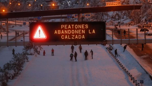 A sign displays a message reading Pedestrians leave the road as people play in the snow on the M-30 motorway, in Madrid, Spain, January 9, 2021. - Sputnik International