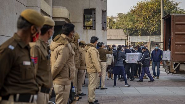 Policemen stand guard as health workers shift a box containing COVID-19 vaccine from a vehicle to a cold storage at Rajiv Gandhi Super Speciality hospital in New Delhi, India, Tuesday, Jan. 12, 2021 - Sputnik International