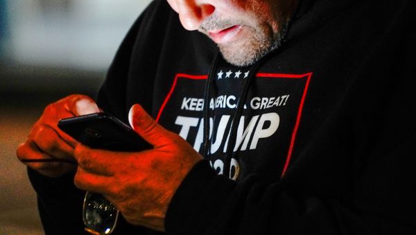 A man wearing a Trump 2020 sweatshirt uses his mobile phone during a Stop the Steal protest outside Milwaukee Central Count - Sputnik International