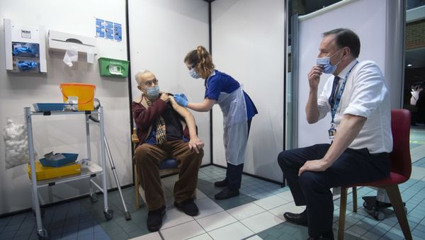 Simon Stevens (R), Chief Executive of the NHS, watches as a nurse (C) administers a dose of the Pfizer-BioNTech Covid-19 vaccine to Frank Naderer (L), 82, at Guy's Hospital in London on 8 December 2020 as the UK starts its biggest ever vaccination programme.  - Sputnik International