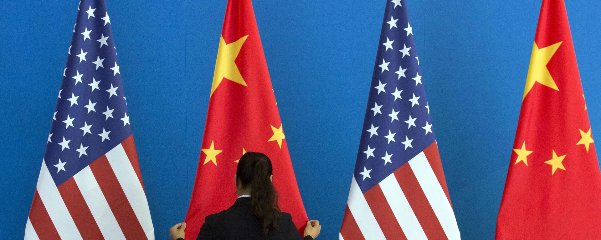A Chinese woman adjusts the Chinese national flag near U.S. national flags before a Strategic Dialogue expanded meeting that's part of the U.S.-China Strategic and Economic Dialogue at the Diaoyutai State Guesthouse in Beijing, Thursday, July 10, 2014 - Sputnik International, 1920, 25.02.2023