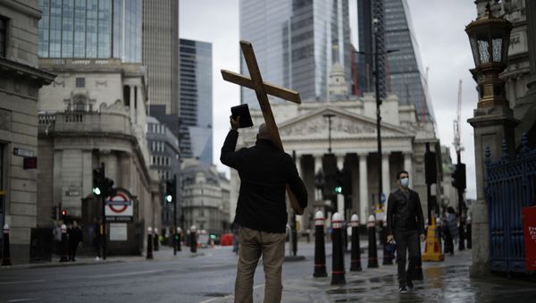 A man holding a cross and a Bible preaches about Christianity backdropped by the Royal Exchange, back center, and the Bank of England, at left, during England's second coronavirus lockdown in the City of London financial district of London, Wednesday, Nov. 18, 2020 A man holding a cross and a Bible preaches about Christianity backdropped by the Royal Exchange, back center, and the Bank of England, at left, during England's second coronavirus lockdown in the City of London financial district of London, Wednesday, Nov. 18, 2020 - Sputnik International