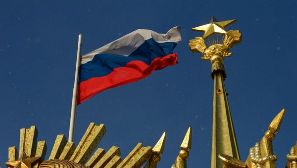 A photograph taken on December 27, 2020 shows the Russian national flag flapping on the wind in front of the Soviet Union symbols placed on the top of a building, in Moscow. - Sputnik International