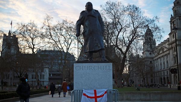 A person wearing a face mask looks at the Winston Churchill statue in Parliament square, in London - Sputnik International