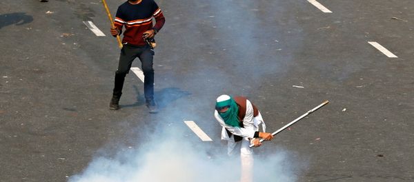 A demonstrator uses a stick to hit a tear gas canister during a protest against farm laws introduced by the government, in New Delhi, India, January 26, 2021 - Sputnik International
