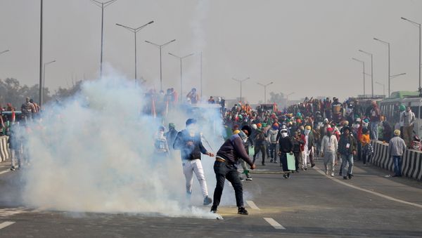 A man throws a tear gas canister back at police during a tractor rally held by farmers to protest farm laws on the occasion of India's Republic Day at Ghazipur border near Delhi - Sputnik International