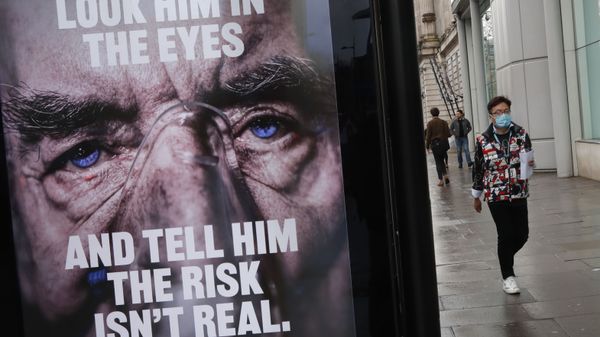 A man wearing a mask against coronavirus walks past an NHS advertisement about COVID-19 in London, Tuesday, Feb. 2, 2021. - Sputnik International