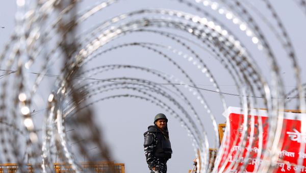 Police officer in riot gear stands guard behind concertina wire at a protest against farm laws at the Delhi-Uttar Pradesh border in Ghaziabad, India - Sputnik International