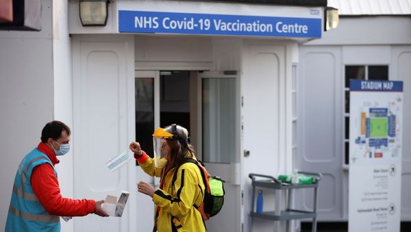 A woman is given a protective face mask as she waits to receive the COVID-19 vaccine at Crystal Palace Football Club Vaccination Centre, amid the outbreak of the coronavirus disease (COVID-19) in London, Britain February 4, 2021. A woman is given a protective face mask as she waits to receive the COVID-19 vaccine at Crystal Palace Football Club Vaccination Centre, amid the outbreak of the coronavirus disease (COVID-19) in London, Britain February 4, 2021. - Sputnik International