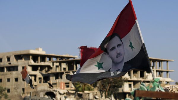 In this July 15, 2018 file photo, a Syrian national flag with a picture of Syrian President Bashar Assad flies at an Army check point, in the town of Douma in the eastern Ghouta region, near Damascus, Syria. - Sputnik International
