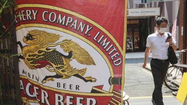 A man walks near an advertisement of a Kirin brand beer in Tokyo, Tuesday, Aug. 25, 2020. Australia's government announced on Tuesday it proposed to block Kirin Holdings Co.'s 45.6 billion yen ($430 million) sale of its Australian beverage unit to a Chinese company in a development likely to increase strain on Chinese-Australian relations. - Sputnik International
