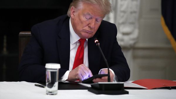 In this Thursday, June 18, 2020 file photo, President Donald Trump looks at his phone during a roundtable with governors on the reopening of America's small businesses, in the State Dining Room of the White House  in Washington. - Sputnik International